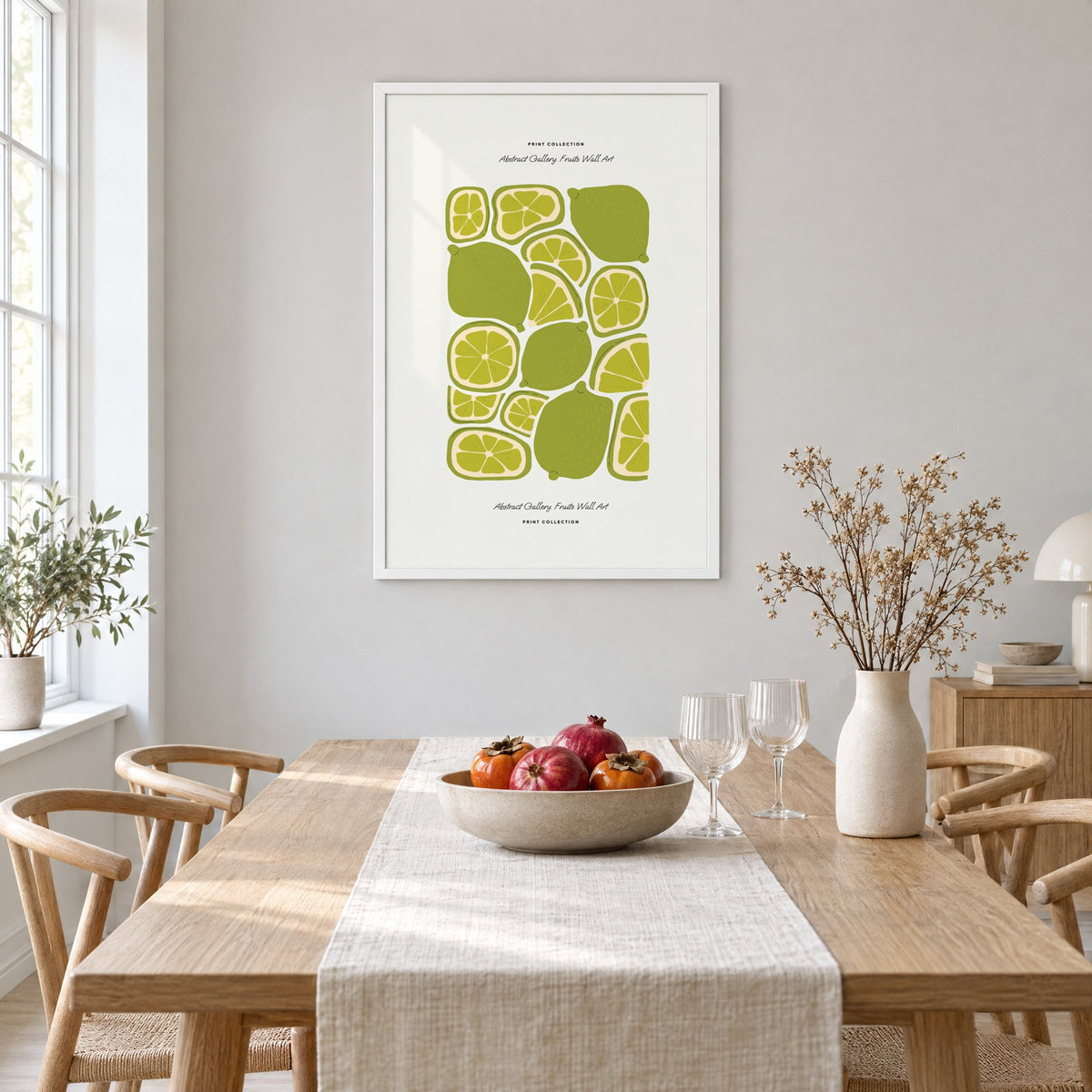 green lime slices pattern fruit print in a white frame above a light oak dining table with a linen runner and fruit bowl