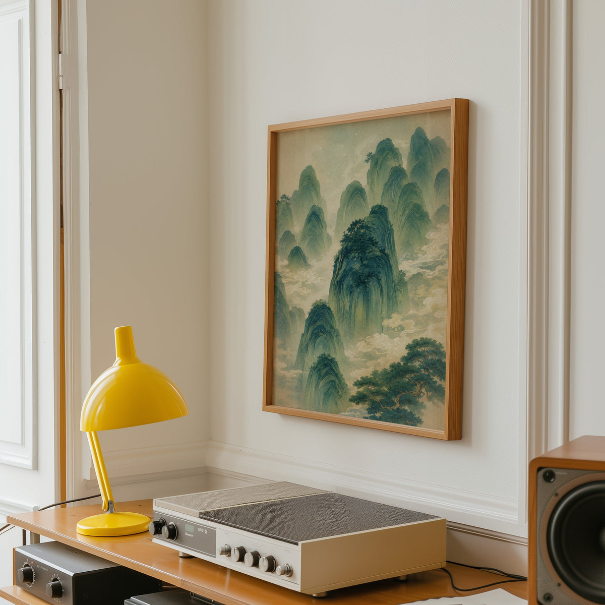 green mountains and clouds landscape print in an oak frame above a vintage hi-fi shelf with a yellow desk lamp