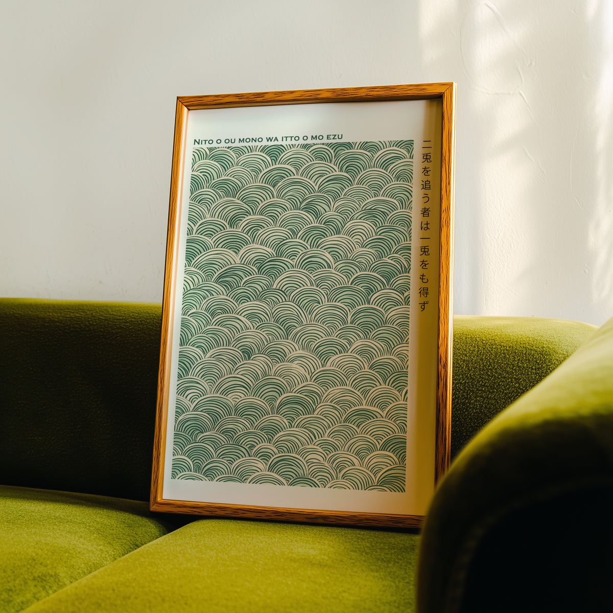 Green seigaiha wave proverb print in an oak frame propped on a green velvet sofa