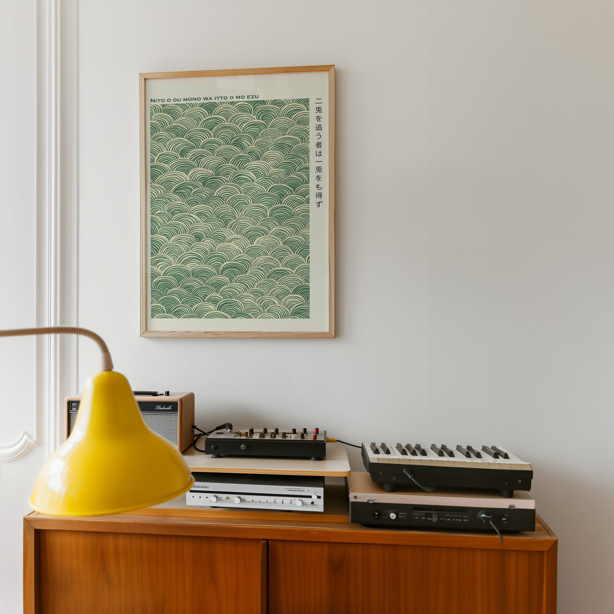 Green seigaiha wave proverb print in an oak frame above a teak sideboard with vintage hi-fi