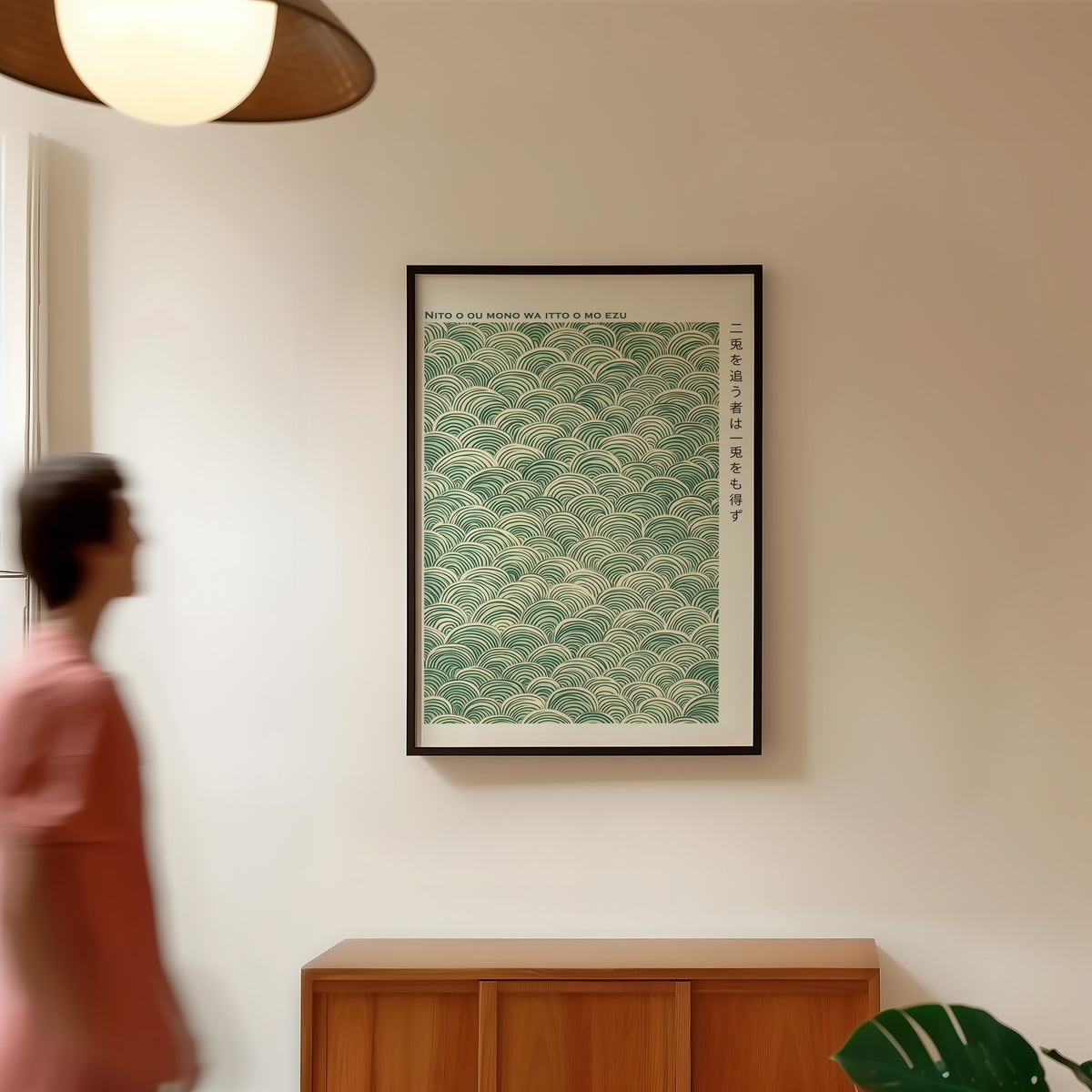 Green seigaiha wave proverb print in a black frame in a hallway under a rattan pendant