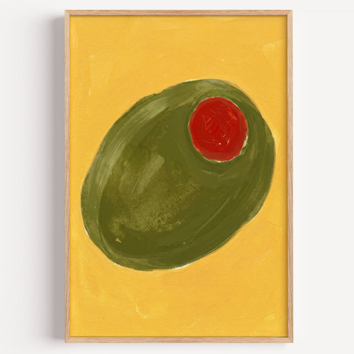 Green stuffed olive print in a light oak frame on a plain white wall