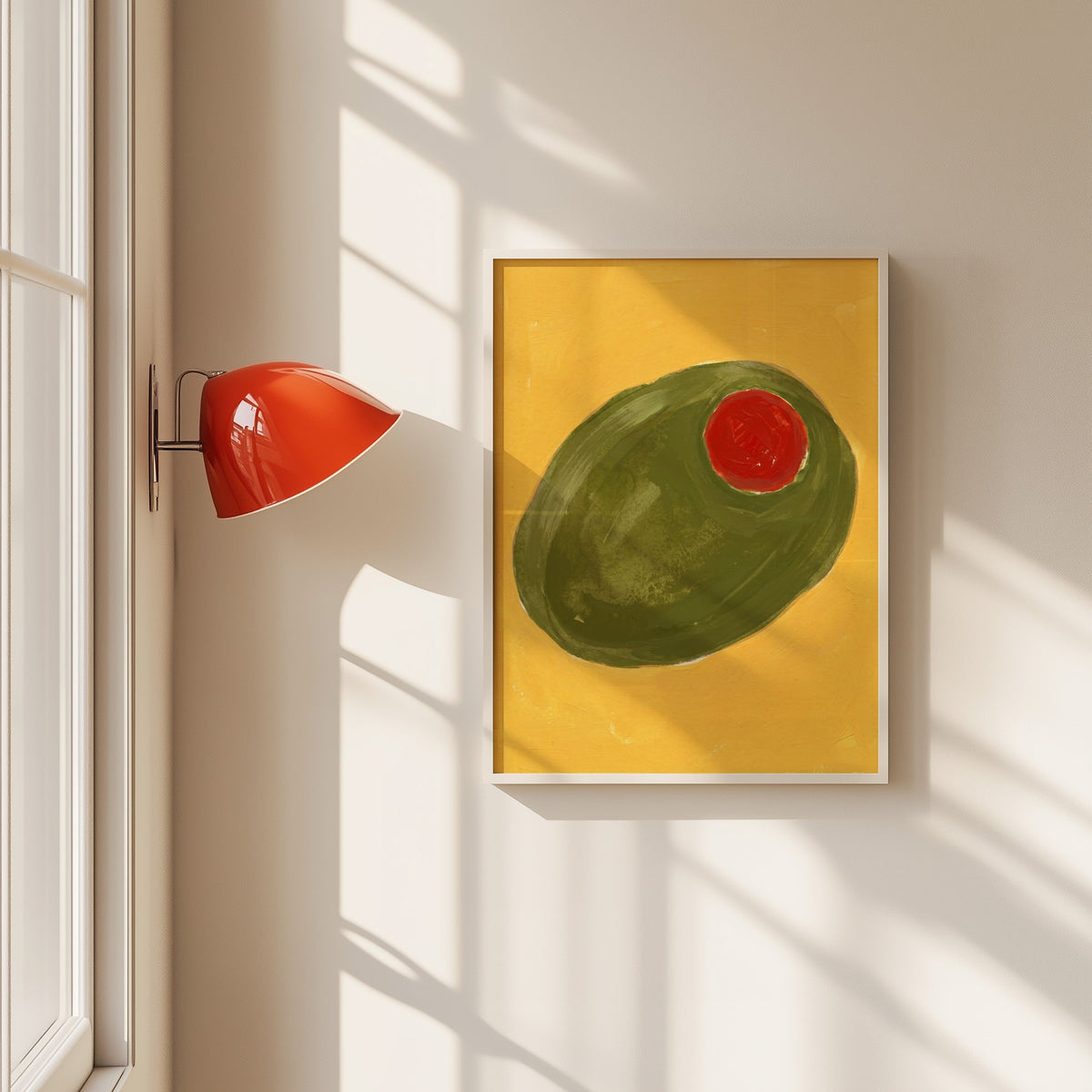 Green stuffed olive print in a white frame beside a red wall sconce