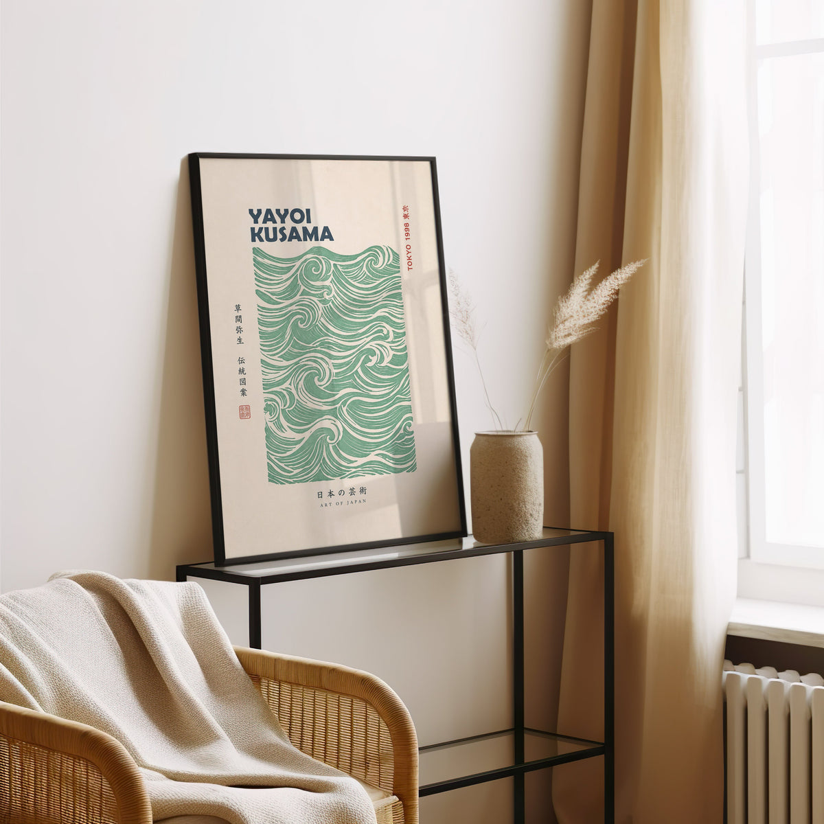 green wave pattern with bold type print in a black frame leaning on a glass console beside pampas grass