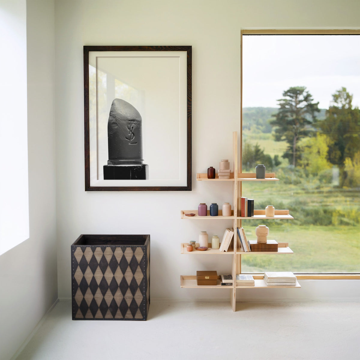 Angled lipstick bullet on plain white print in a walnut frame with a white mat beside wooden shelves and a garden window