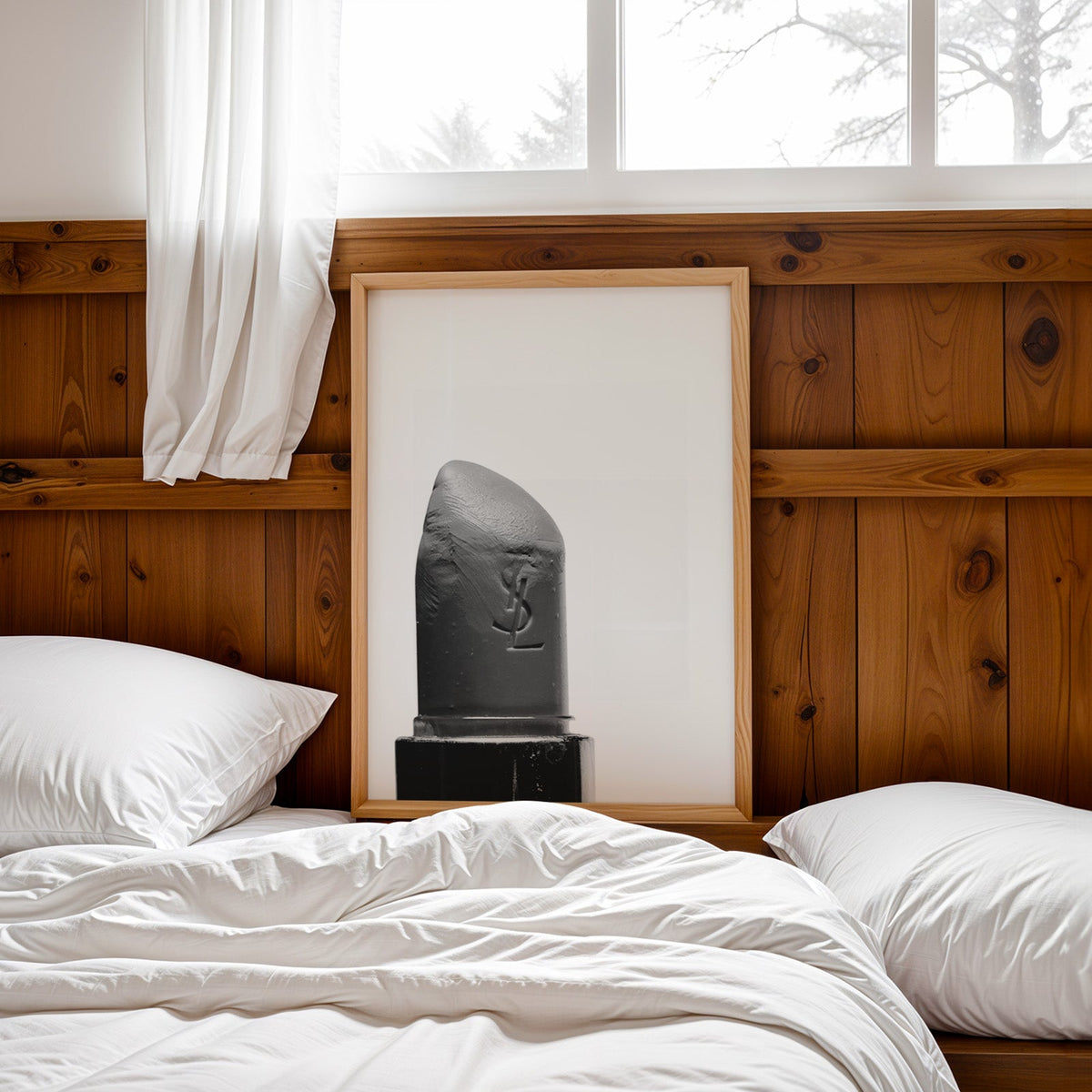 Angled lipstick bullet on plain white print in a pine frame leaning on a wood headboard over white bedding