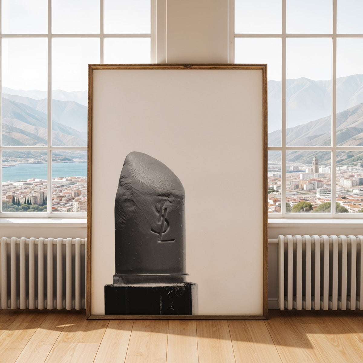 Angled lipstick bullet on plain white print shown in an antique gold frame by tall windows with a sea view