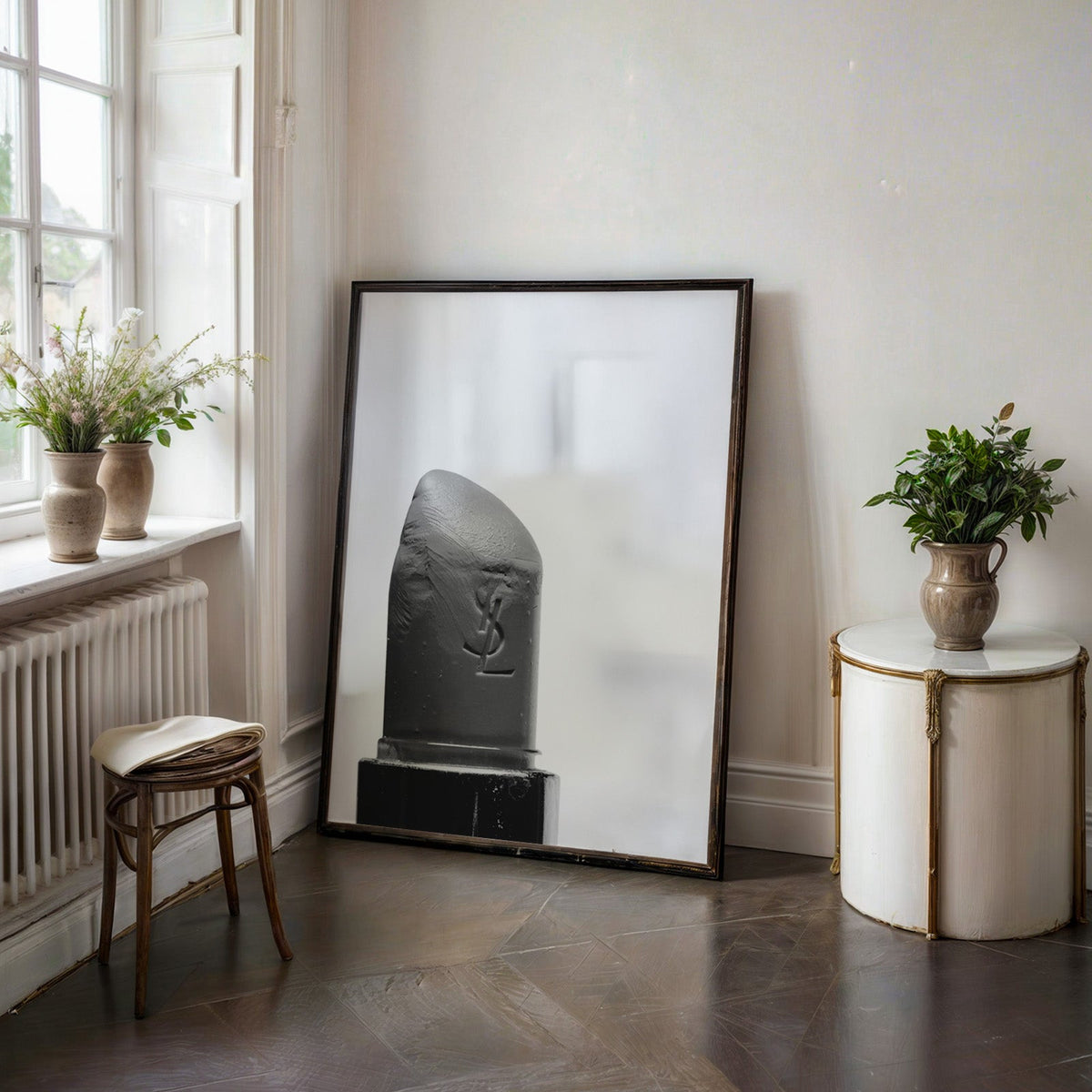 Angled lipstick bullet on plain white print in a black frame on a dark stone floor beside a white side table