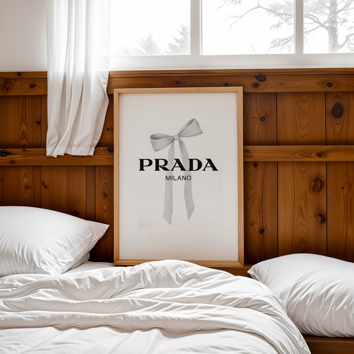 Soft grey silk bow with long ribbon tails print in a pine frame leaning on a wood headboard over white bedding