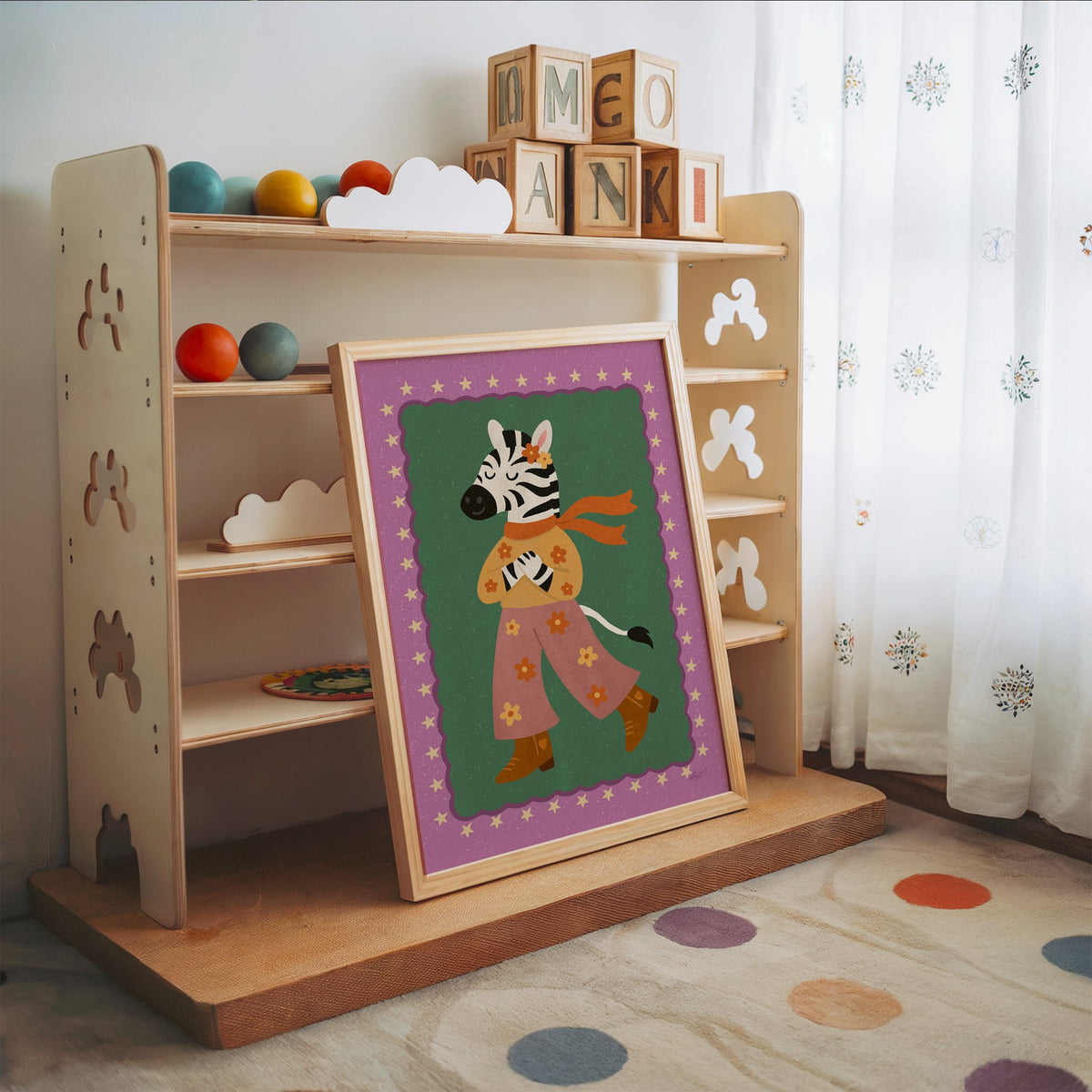 Groovy zebra in flower pants nursery print in an oak frame leaning on a toy shelf with wooden letter blocks