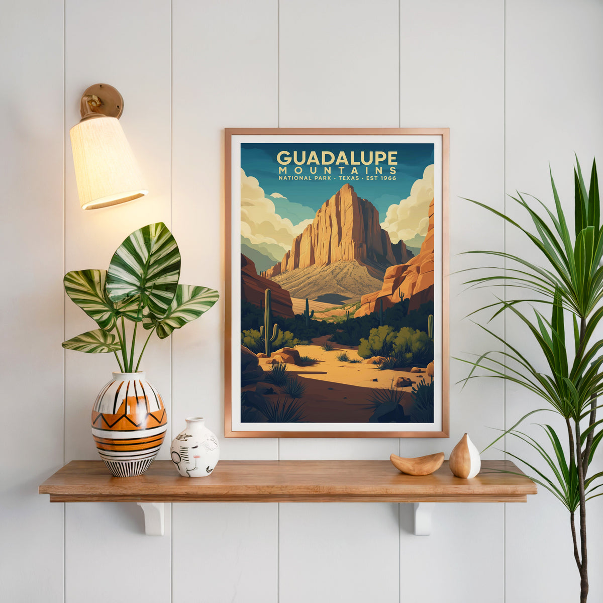 Guadalupe Mountains print in a copper frame above an oak shelf on white shiplap with a sconce