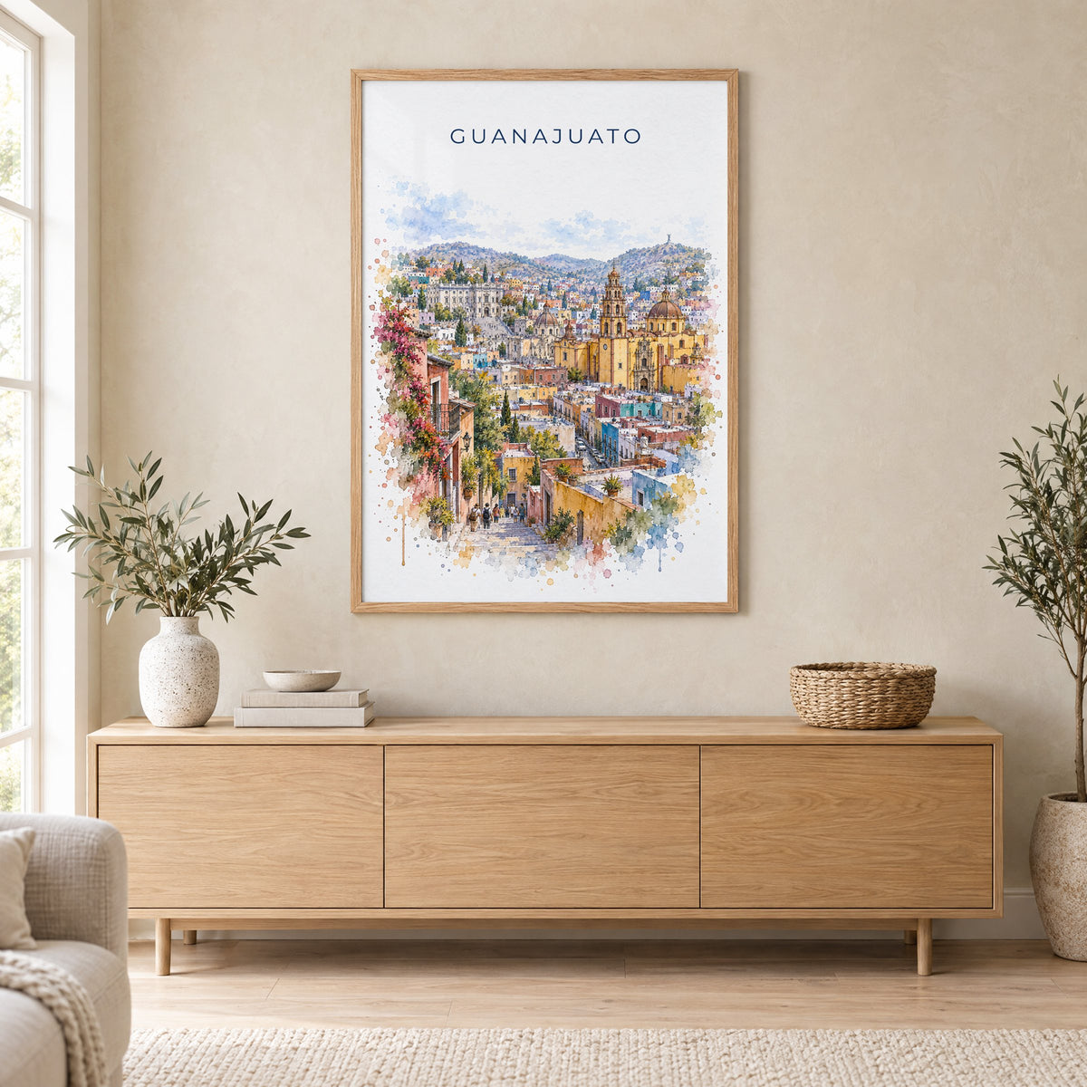 Guanajuato watercolor print in an oak frame above a light wood sideboard in a Scandinavian living room