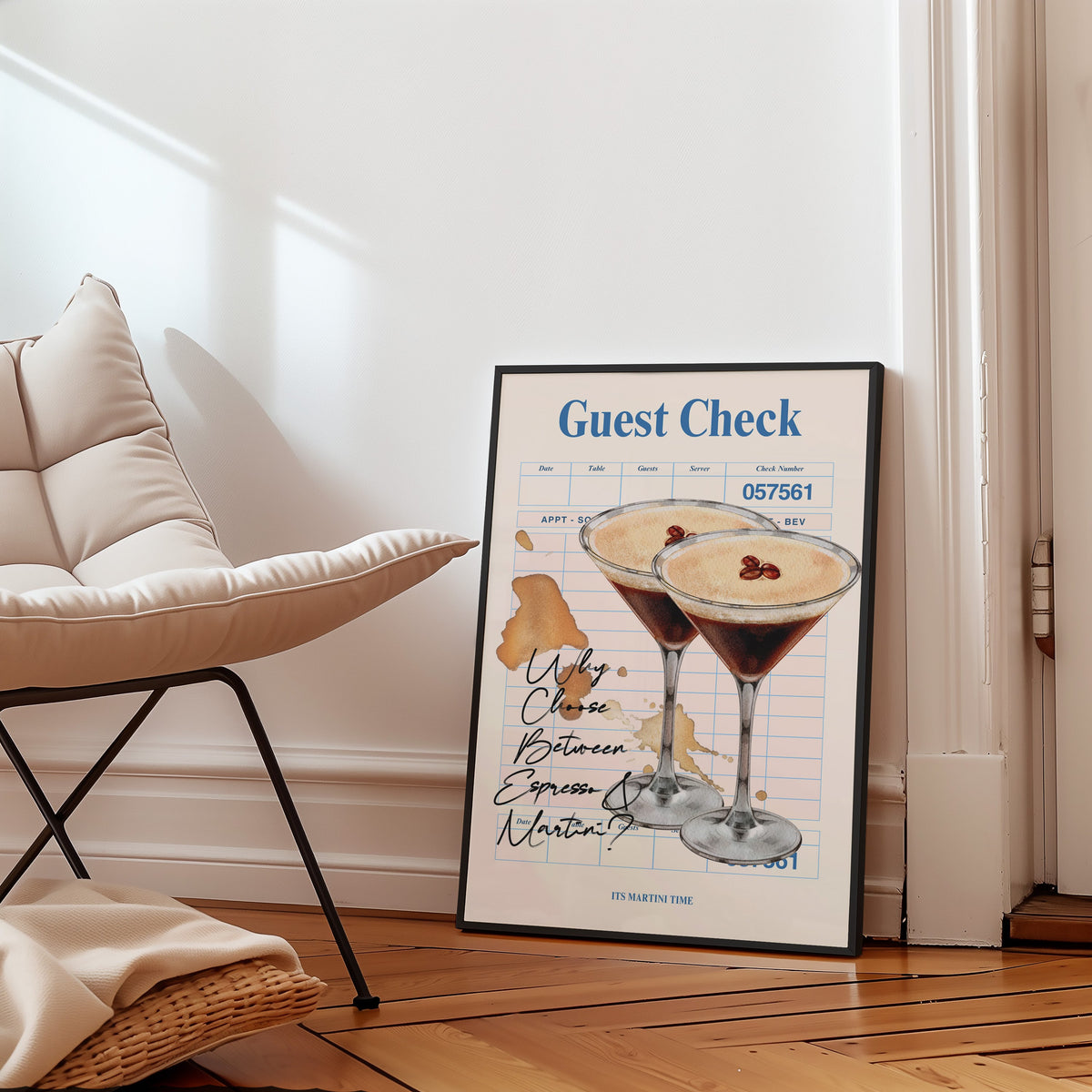 Guest check espresso martini print in a slim black frame leaning on a herringbone floor beside a cream armchair
