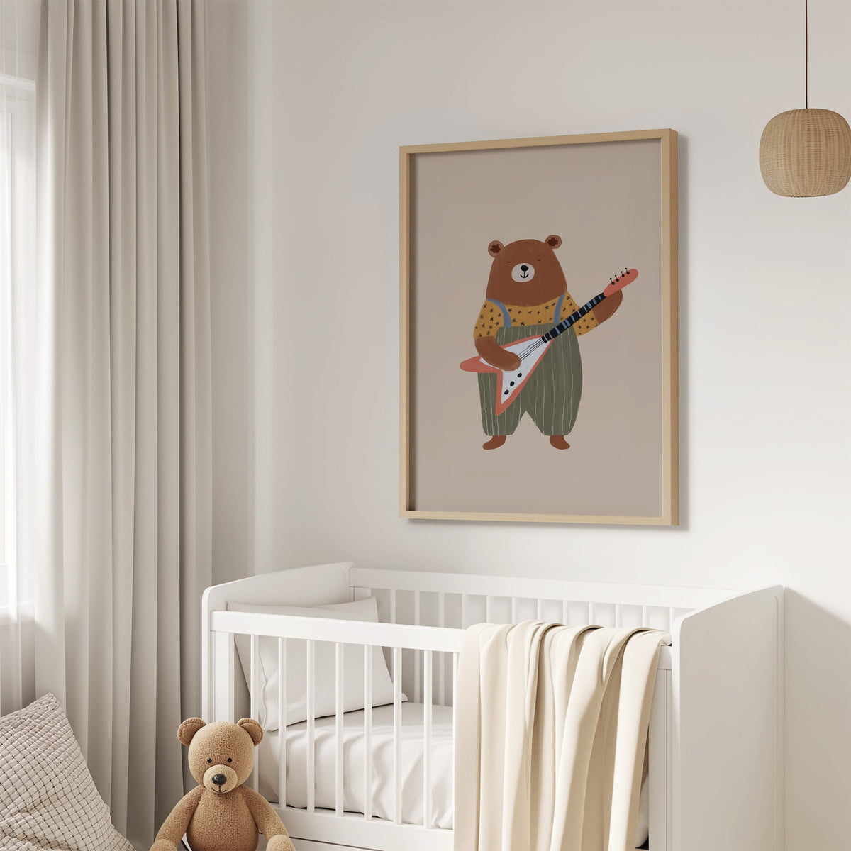 Guitar bear green overalls nursery print in an oak frame above a white crib with a teddy bear