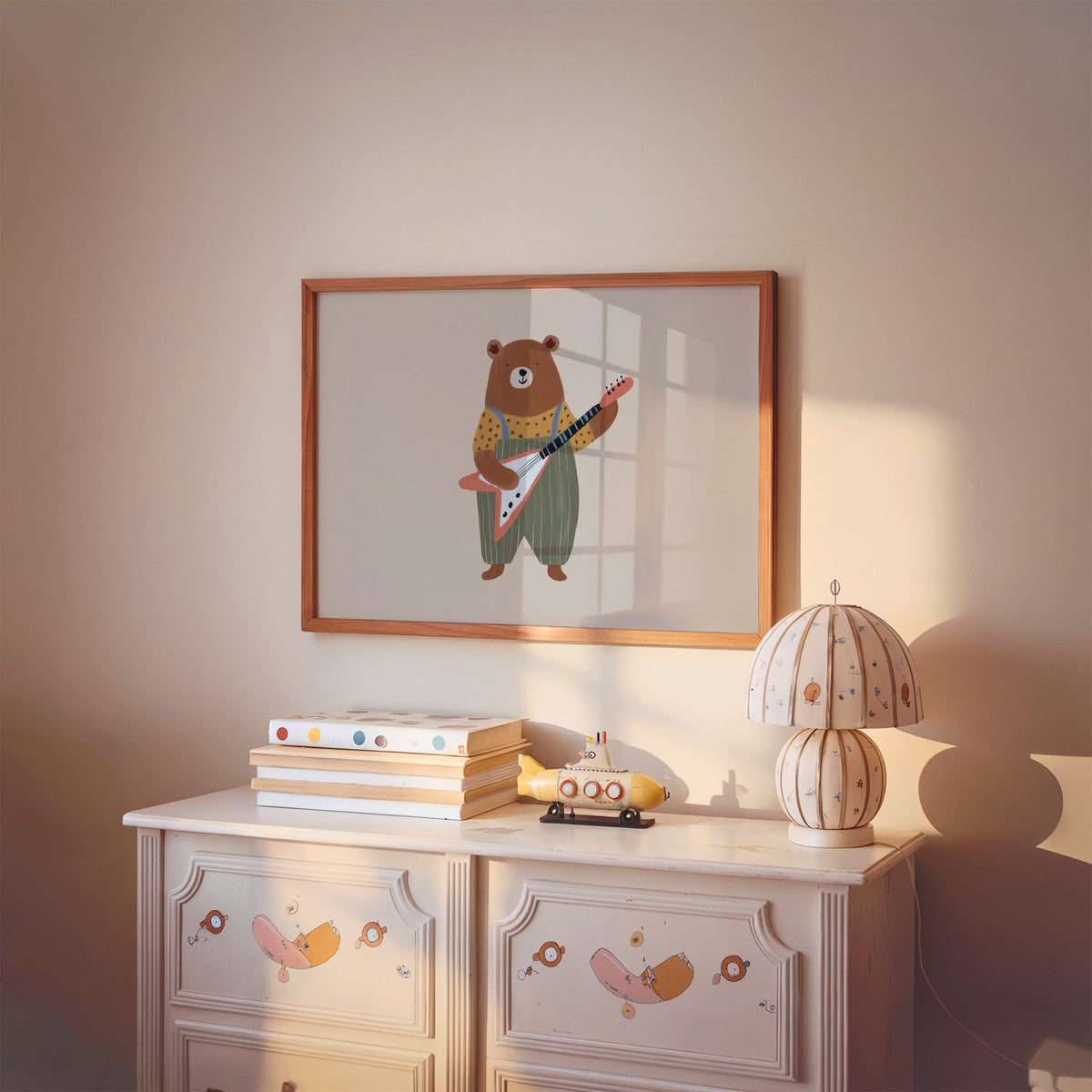Landscape guitar bear green overalls nursery print in a cherry wood frame above a painted dresser and lamp