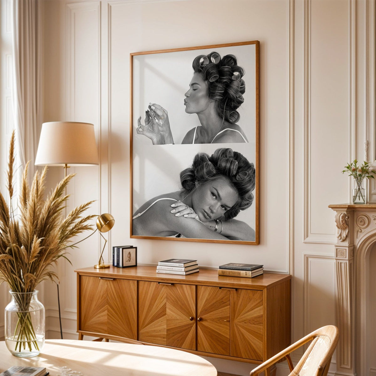 Woman in hair rollers with heart locket two frames print in an oak frame above a sunburst wood sideboard with pampas grass