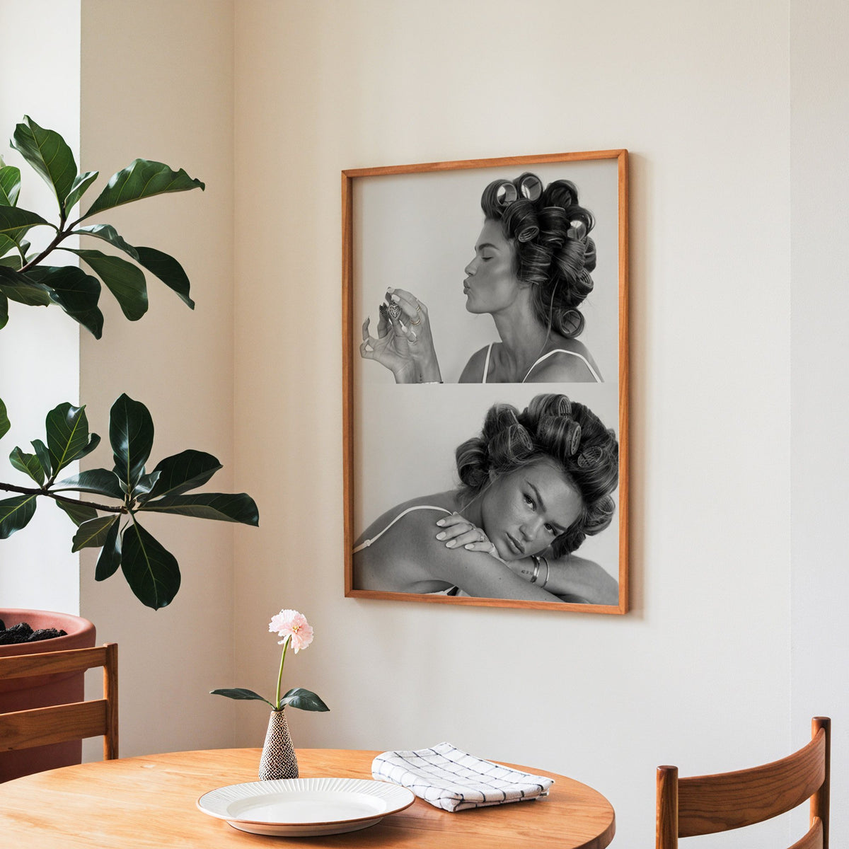 Woman in hair rollers with heart locket two frames print in a teak frame above a round wooden dining table