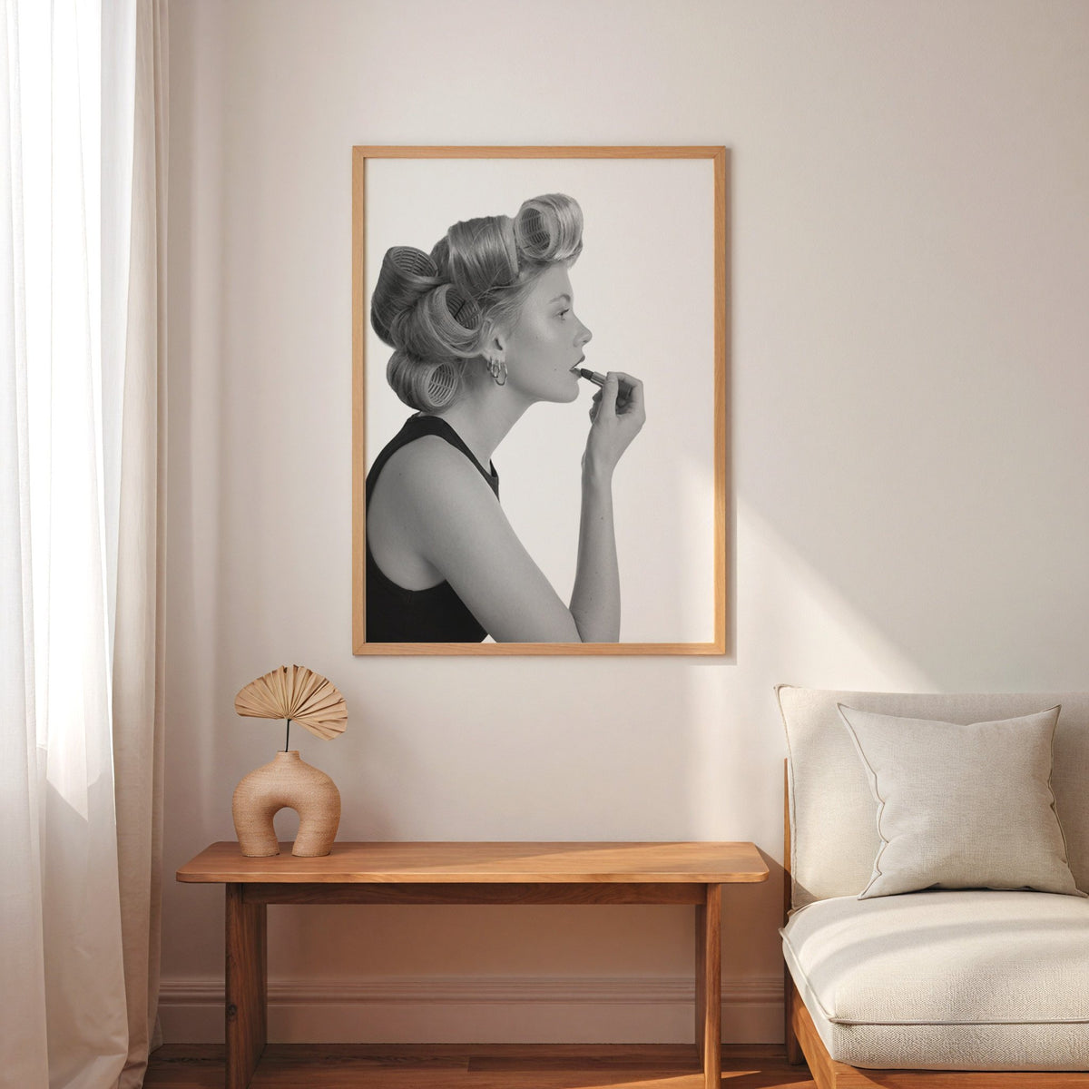 Woman in hair rollers applying lipstick profile print in an oak frame above a narrow console with an arched vase