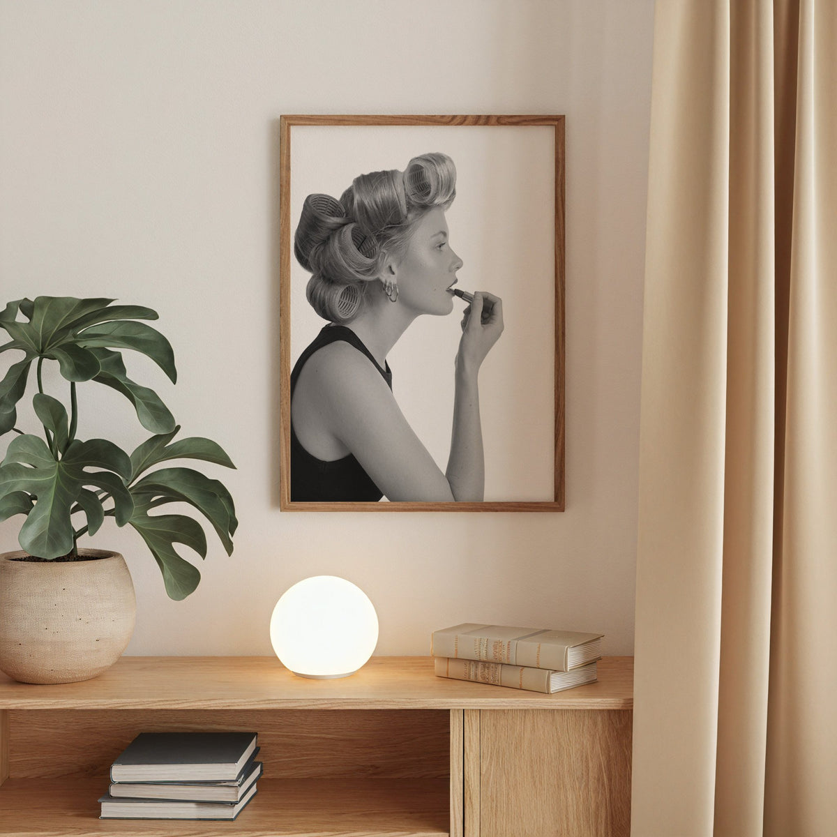 Woman in hair rollers applying lipstick profile print in a walnut frame above an oak cabinet with a glowing globe lamp