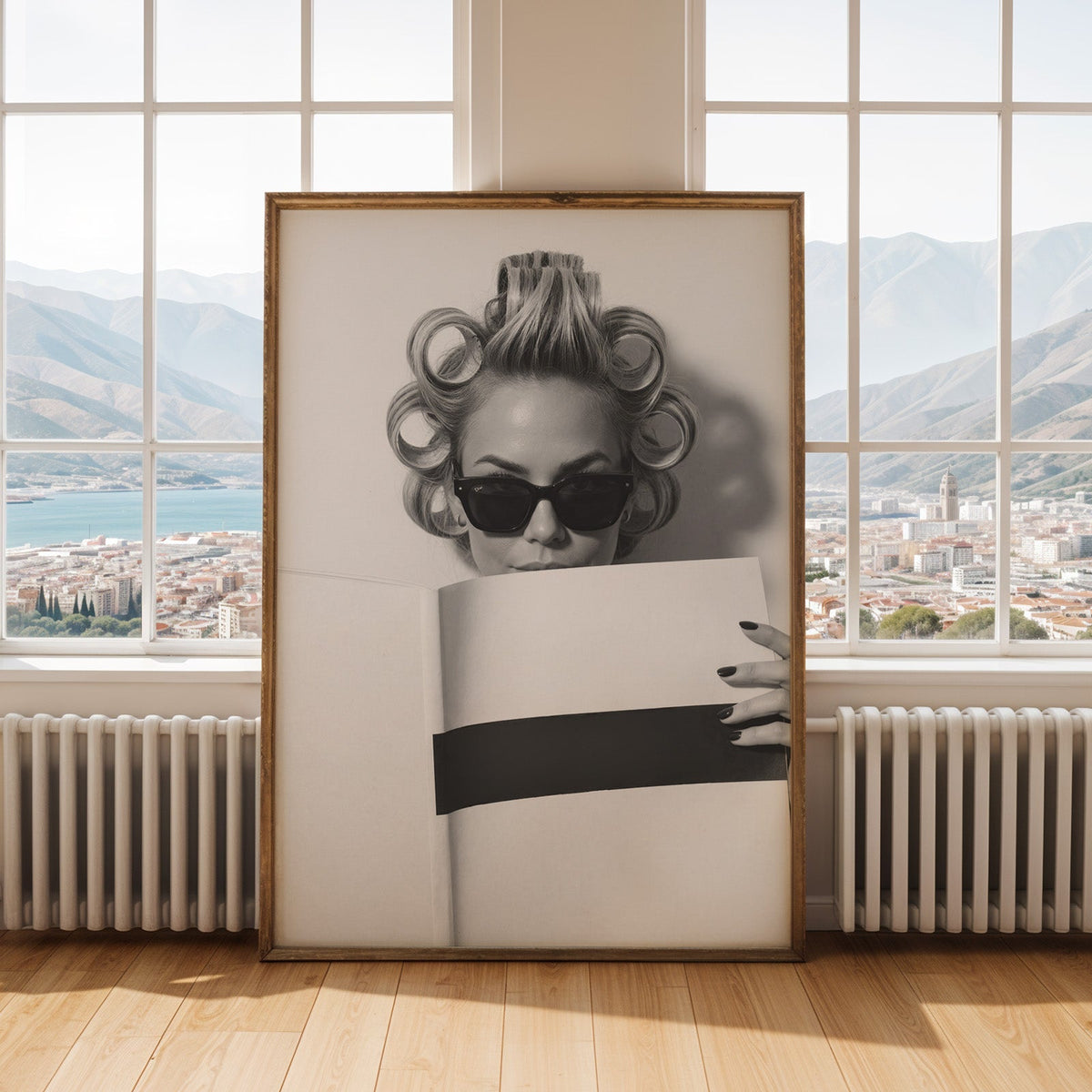 Woman in hair rollers and sunglasses with page print shown in an antique gold frame by tall windows with a sea view