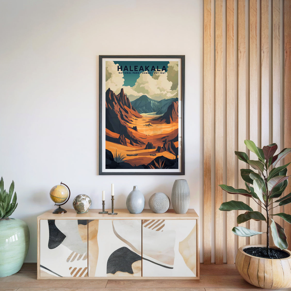 Haleakalā National Park print in a black frame above a light wood sideboard with a globe