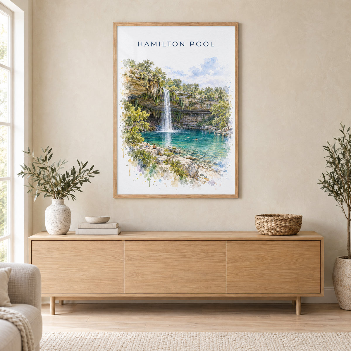 Hamilton Pool watercolor print in an oak frame above a light wood sideboard in a Scandinavian living room