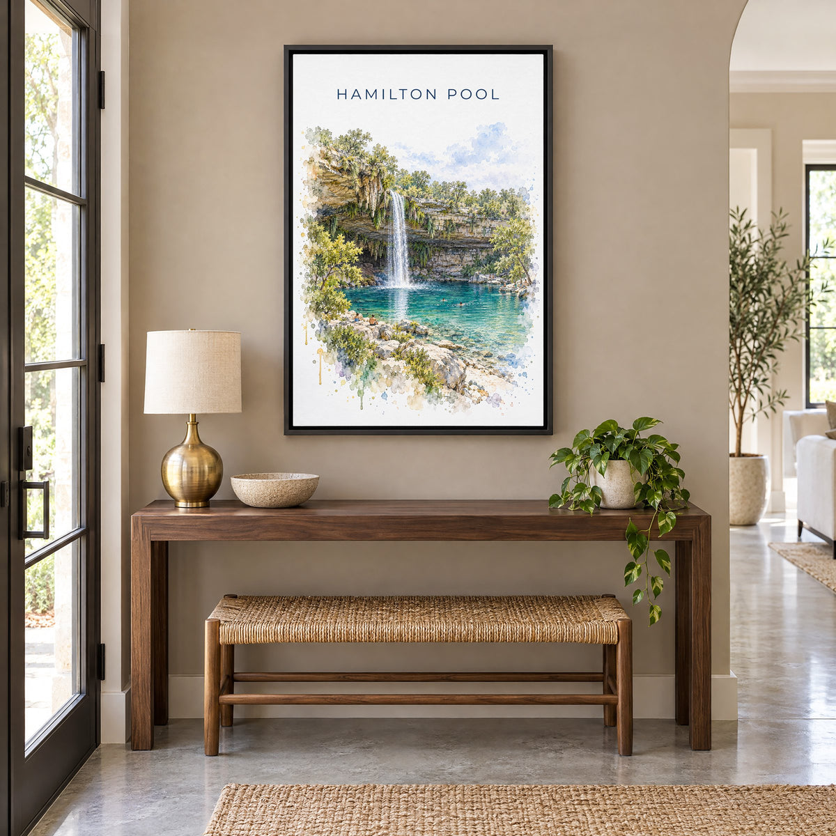 Hamilton Pool watercolor print as a black floater canvas above a walnut console and woven bench in an entryway