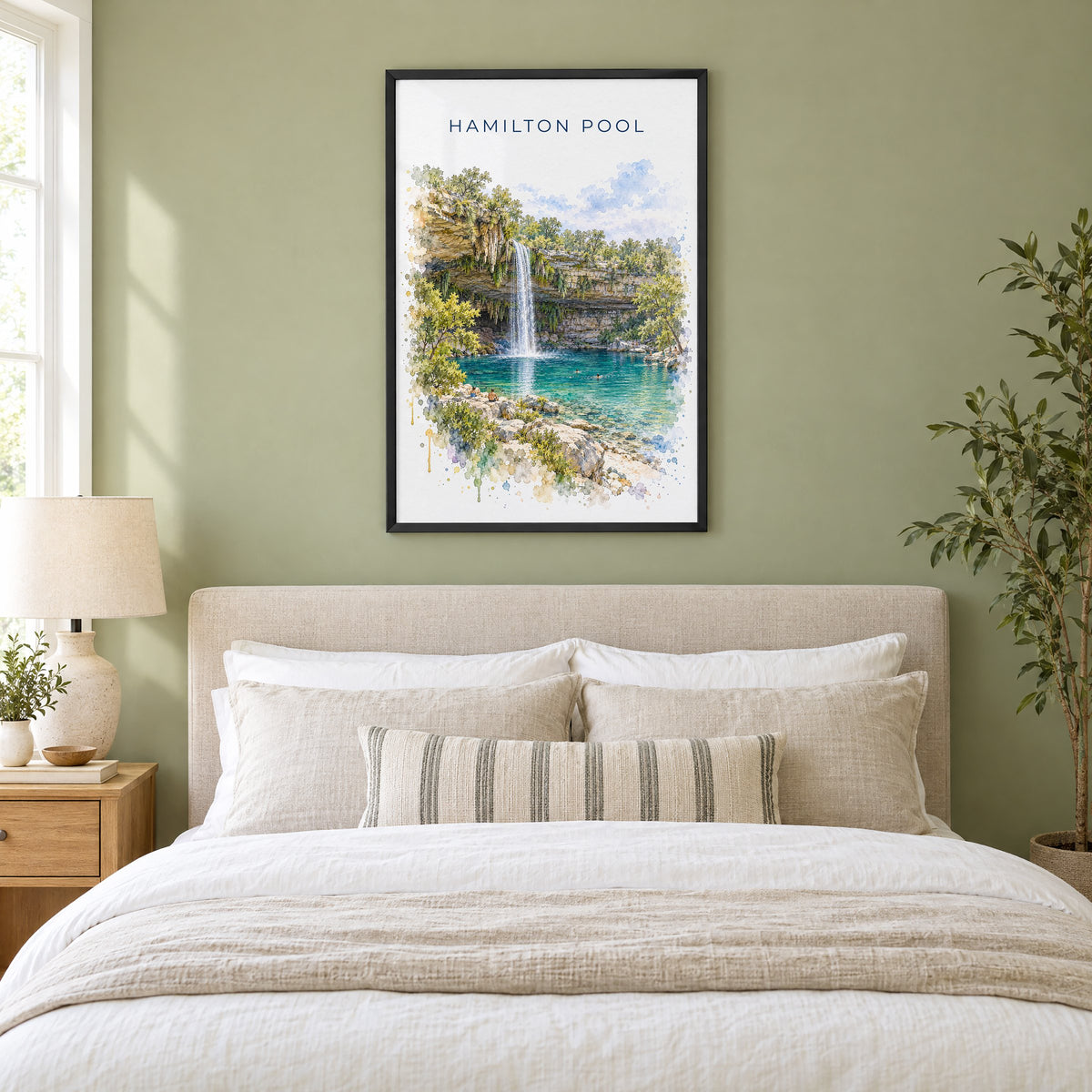 Hamilton Pool watercolor print in a black frame above an upholstered headboard in a sage green bedroom
