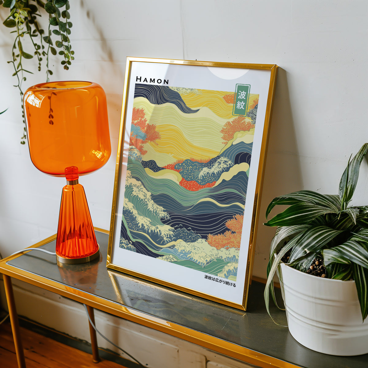 Colorful Hamon ripple wave print shown in a gold frame on a console beside an orange glass lamp