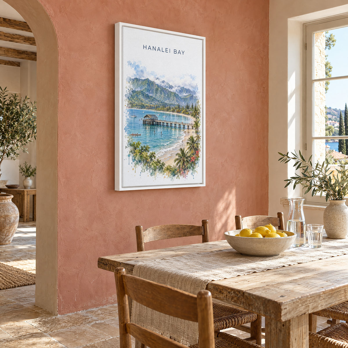 Hanalei Bay watercolor print as a white floater canvas on a terracotta wall above a rustic dining table
