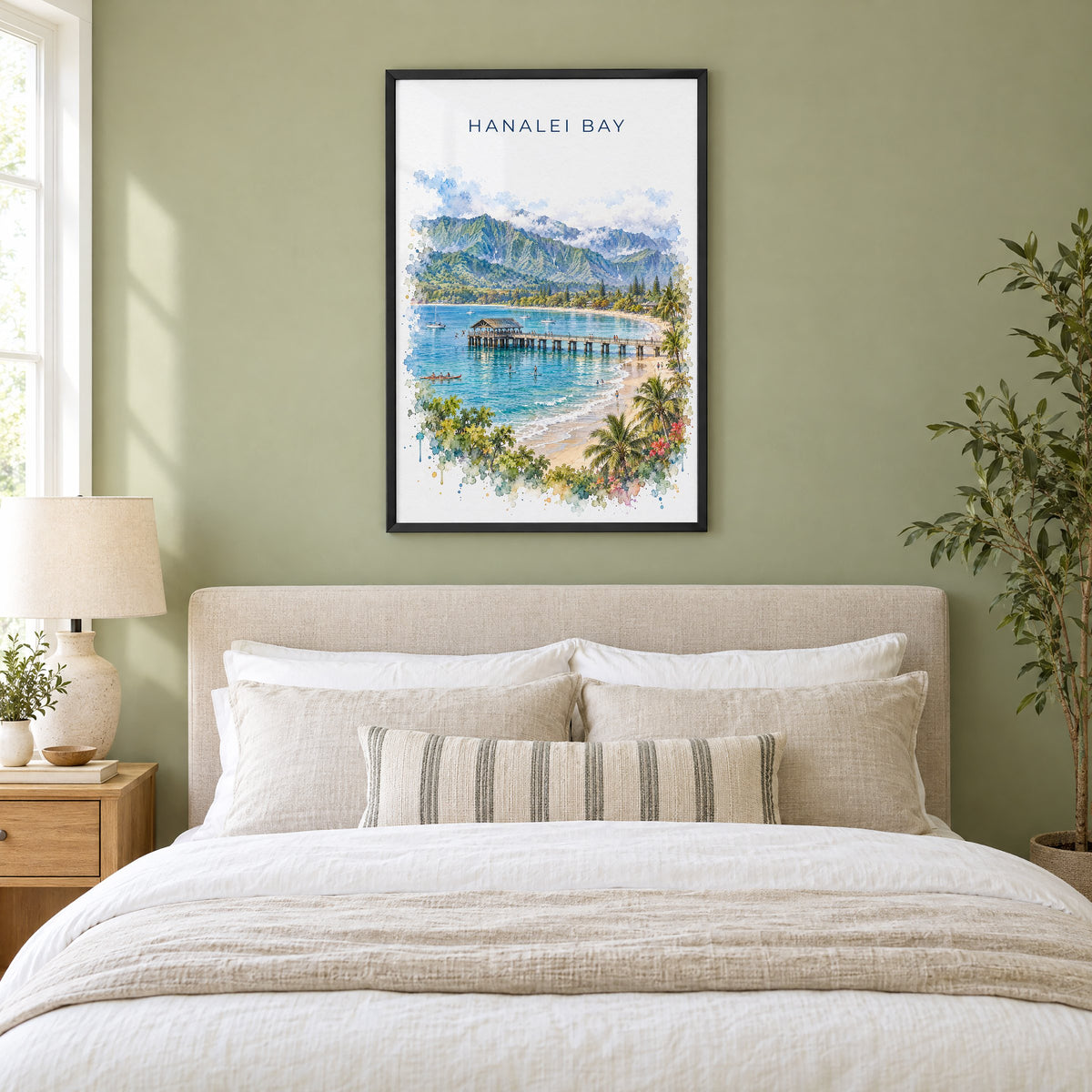 Hanalei Bay watercolor print in a black frame above an upholstered headboard in a sage green bedroom