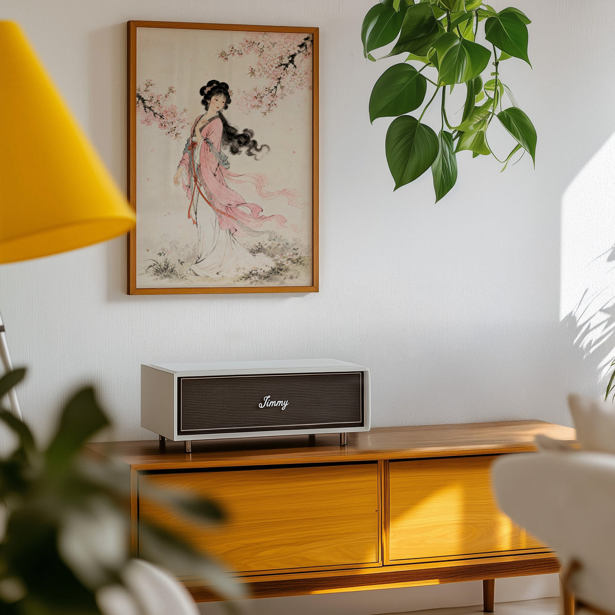 woman in pink hanfu under blossom print in an oak frame above a teak mid-century sideboard with trailing pothos
