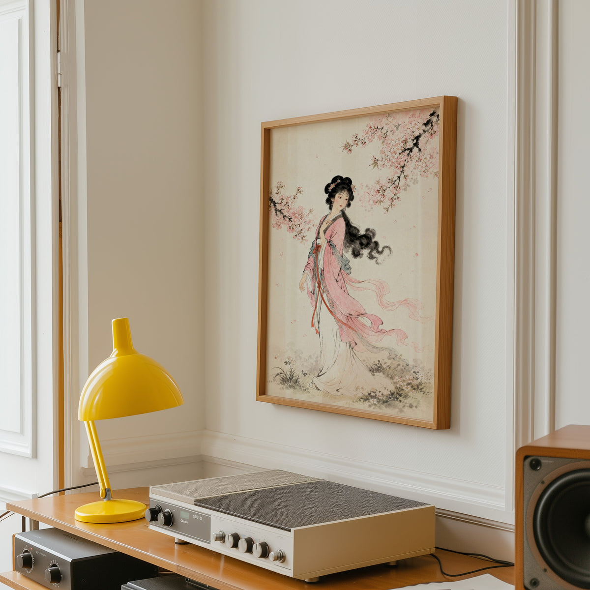 woman in pink hanfu under blossom print in an oak frame above a vintage hi-fi shelf with a yellow desk lamp