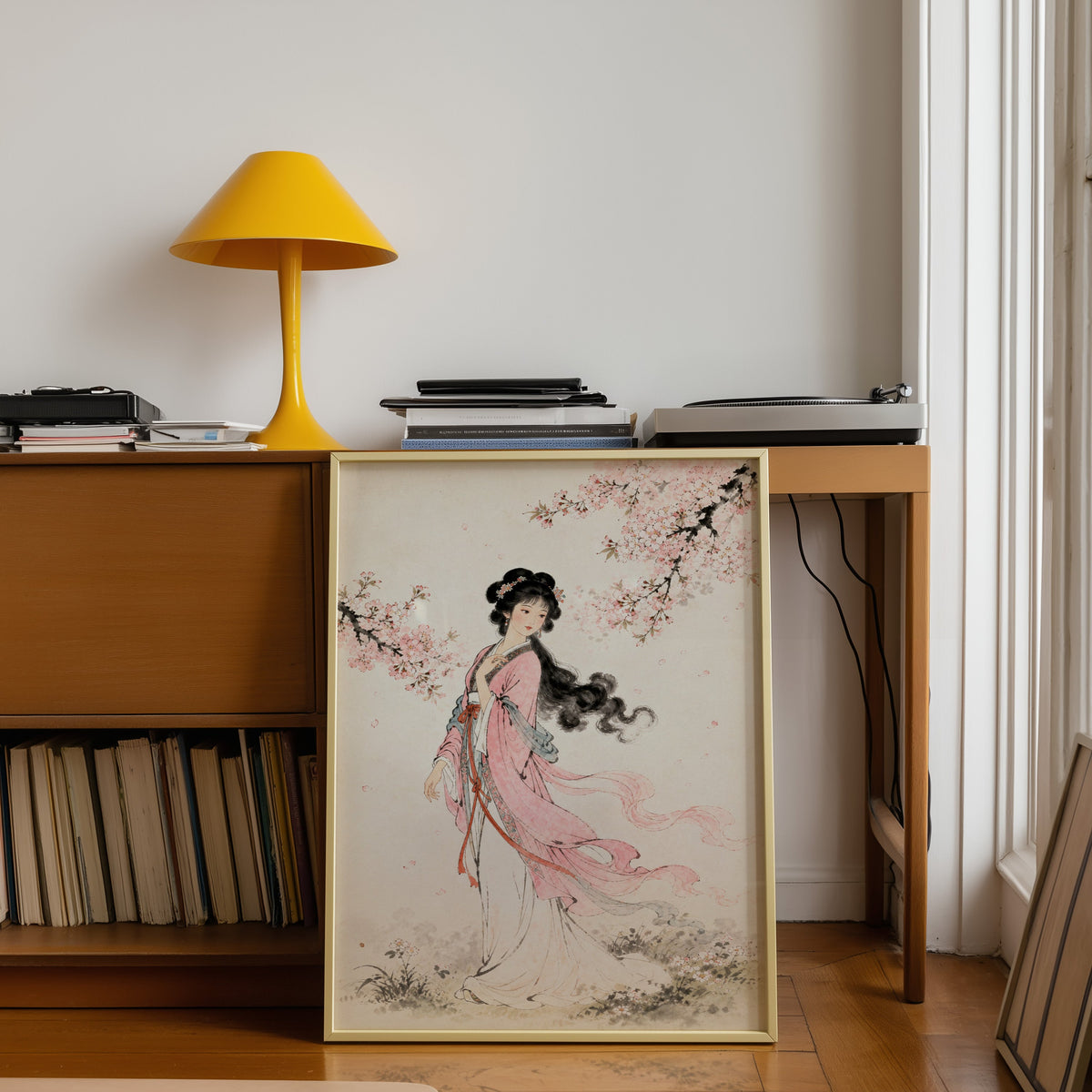 woman in pink hanfu under blossom print shown in a gold frame leaning under a teak desk with a yellow lamp