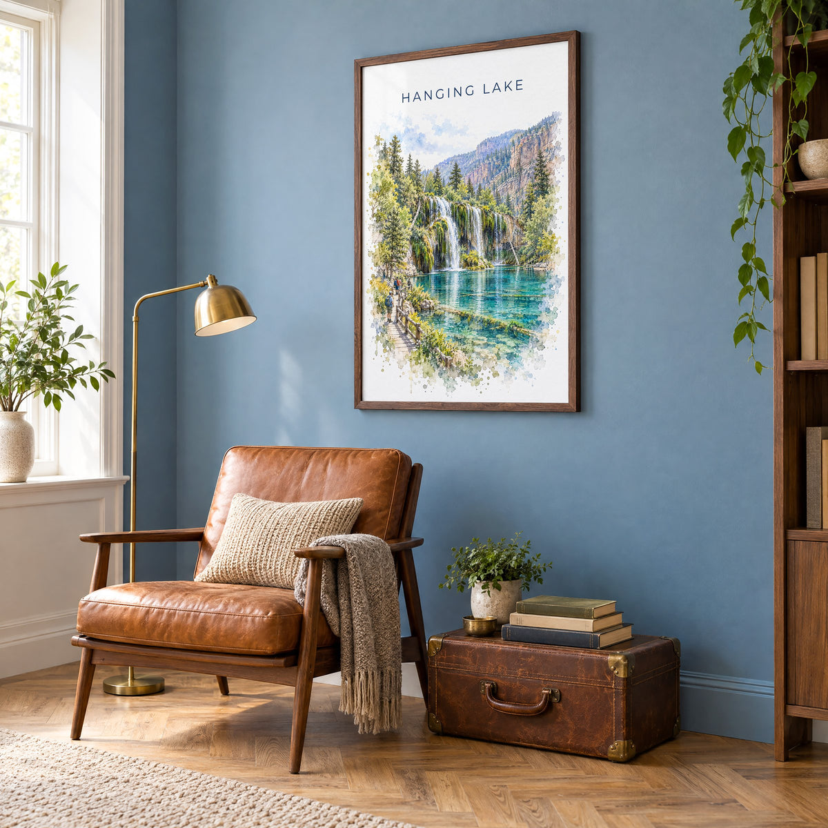 Hanging Lake watercolor print in a walnut frame on a blue wall above a leather armchair in a reading nook