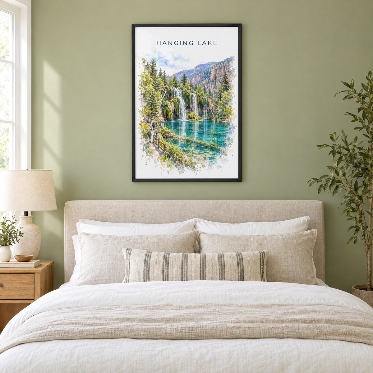 Hanging Lake watercolor print in a black frame above an upholstered headboard in a sage green bedroom