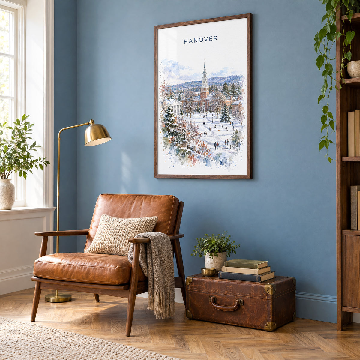Hanover, New Hampshire watercolor print in a walnut frame on a blue wall above a leather armchair in a reading nook