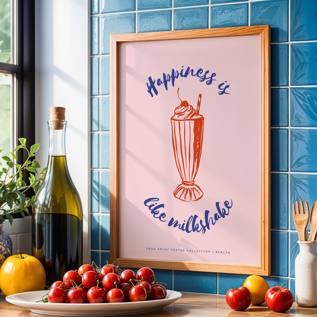 Milkshake print in an oak frame against blue kitchen tiles with olive oil and cherries