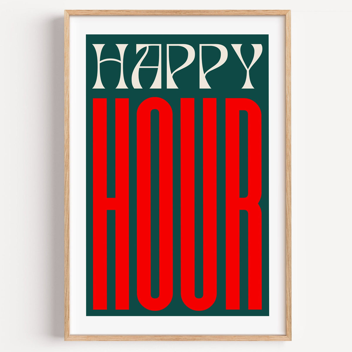 Happy Hour red and teal type print in a light oak frame on a plain white wall