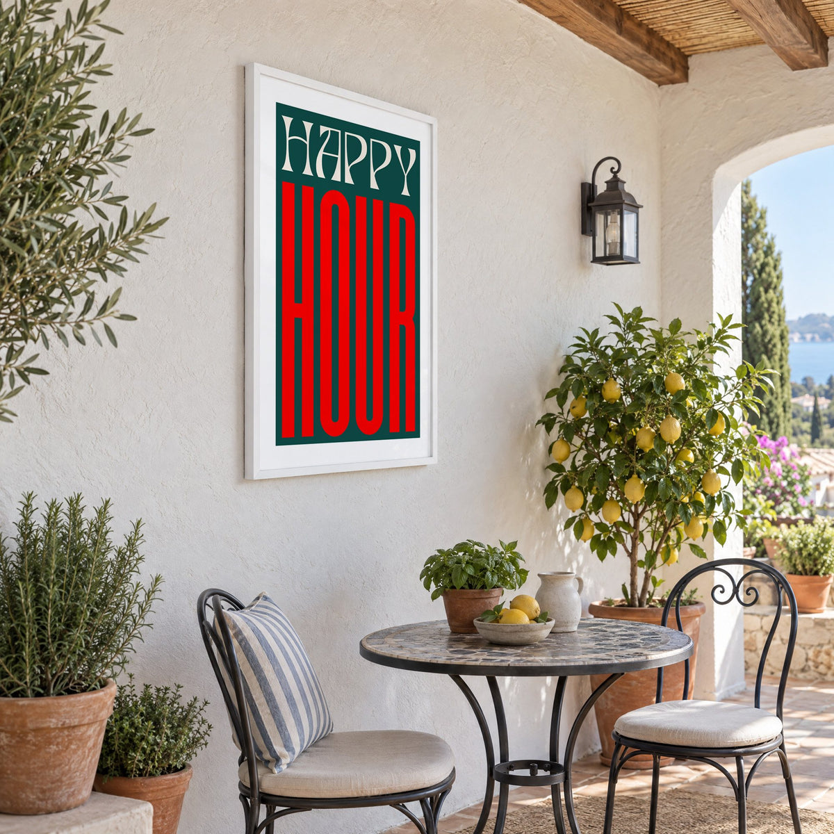 Happy Hour red and teal type print in a white frame on a sunny patio wall beside a potted lemon tree