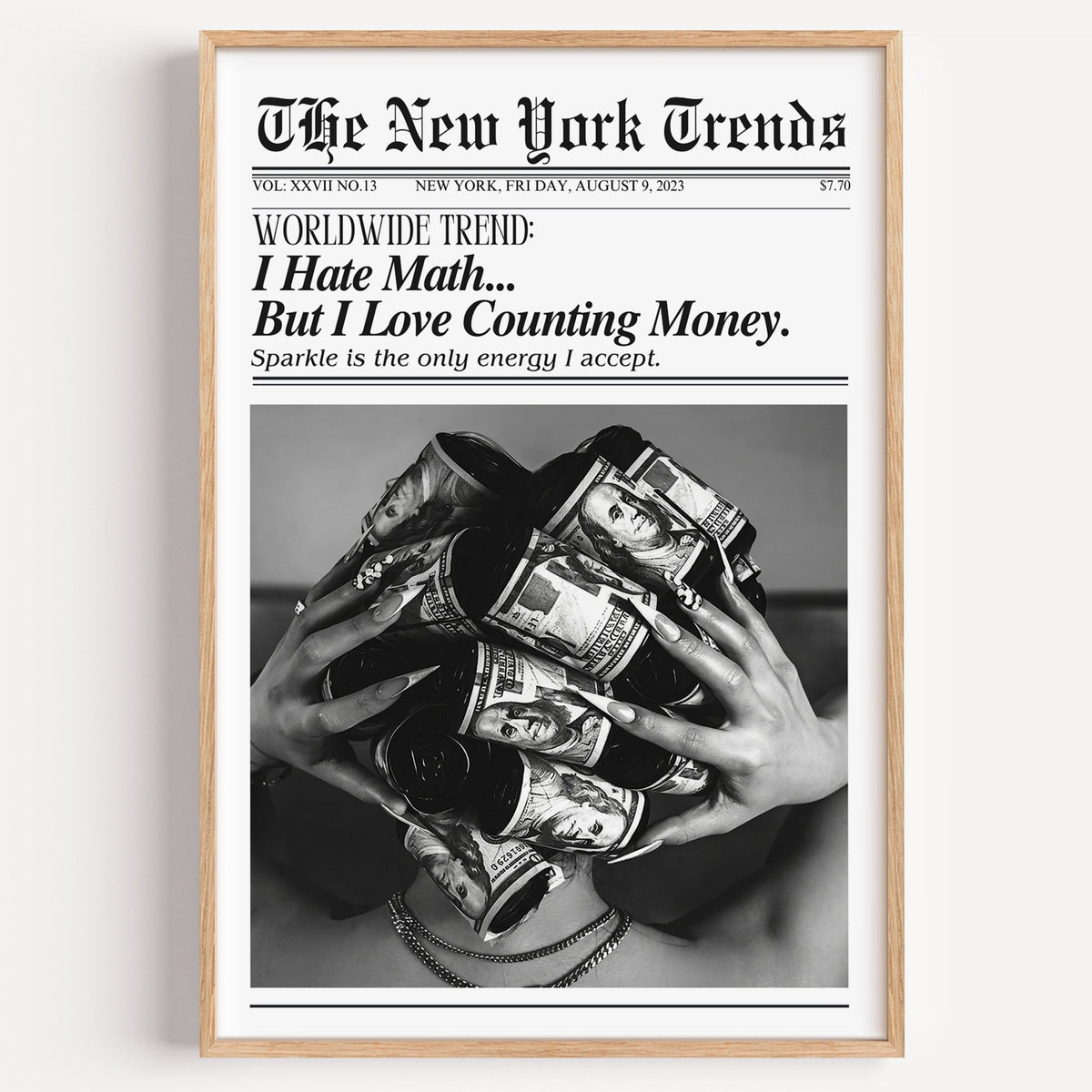 Dollar bill hair rollers mock newspaper print in a light oak frame on a plain white wall