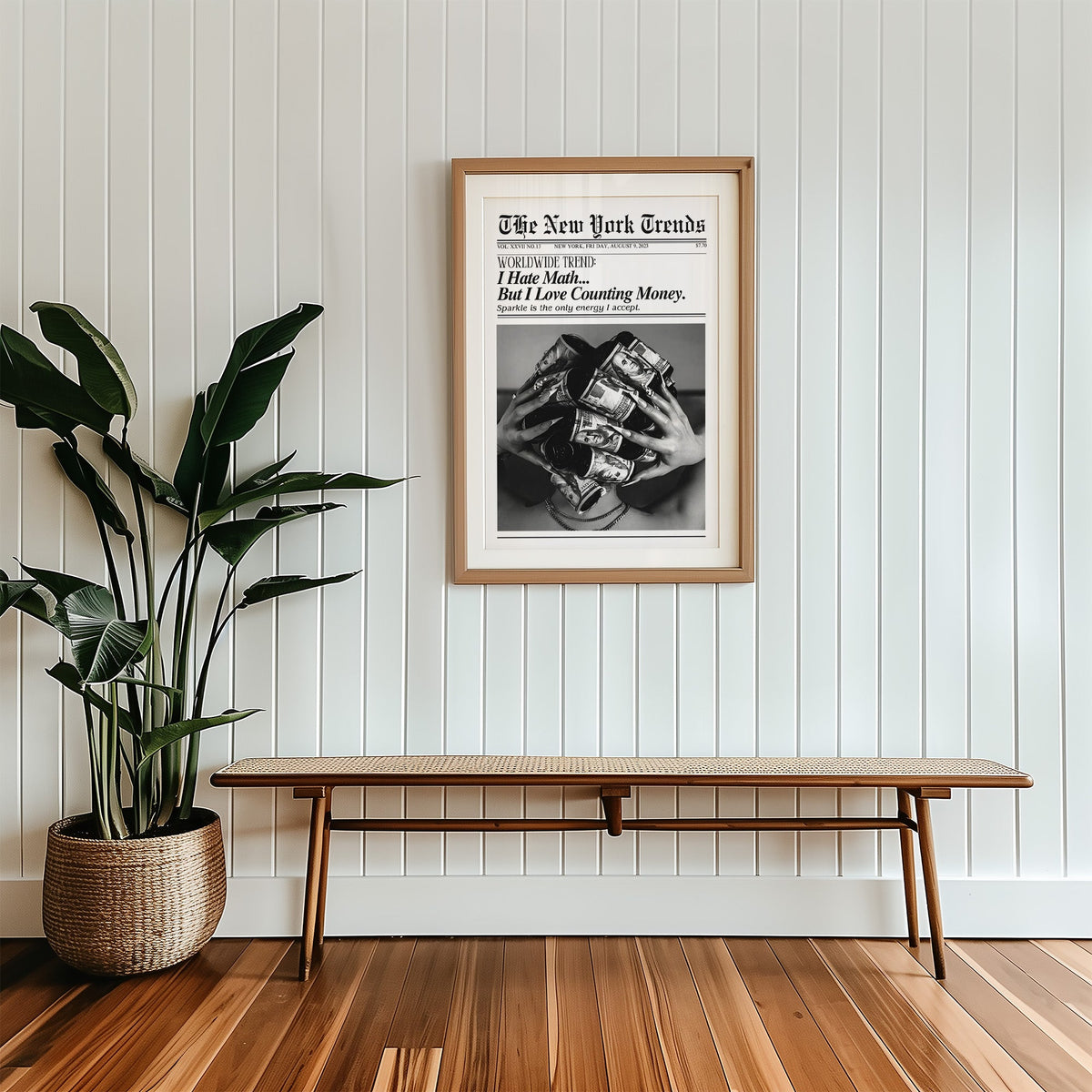 Dollar bill hair rollers mock newspaper print in a wood frame with a white mat above a cane bench