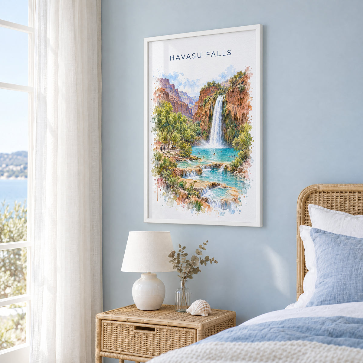 Havasu Falls watercolor print in a white frame on a pale blue wall beside a rattan bed in a coastal bedroom