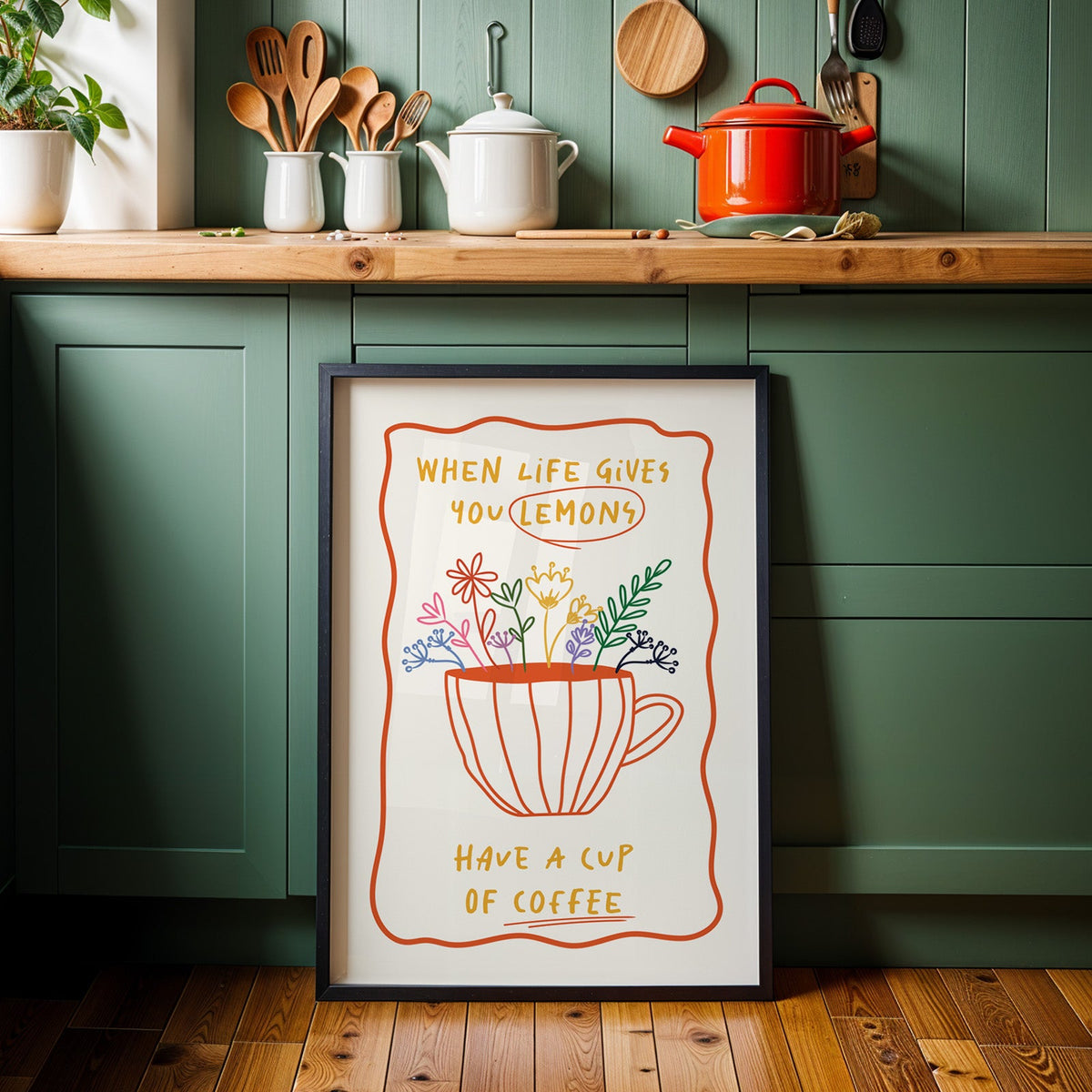Have a cup of coffee print in a black frame against sage green kitchen cabinets