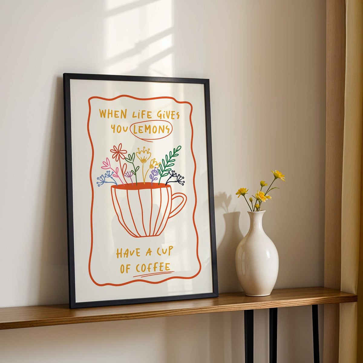 Have a cup of coffee print in a black frame on a console table with yellow daisies