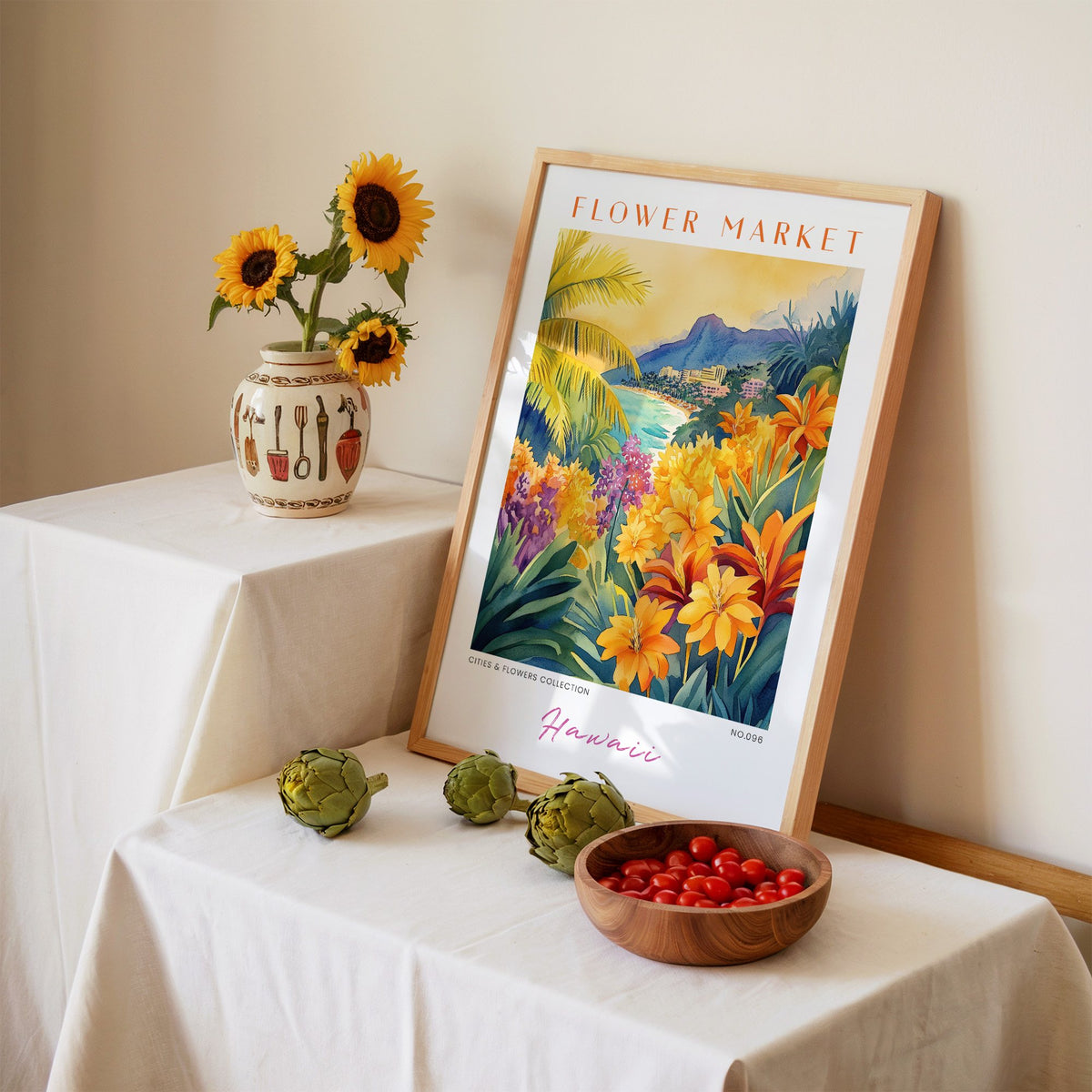 Hawaii flower market print in an oak frame leaning on a linen-draped table beside a vase of sunflowers