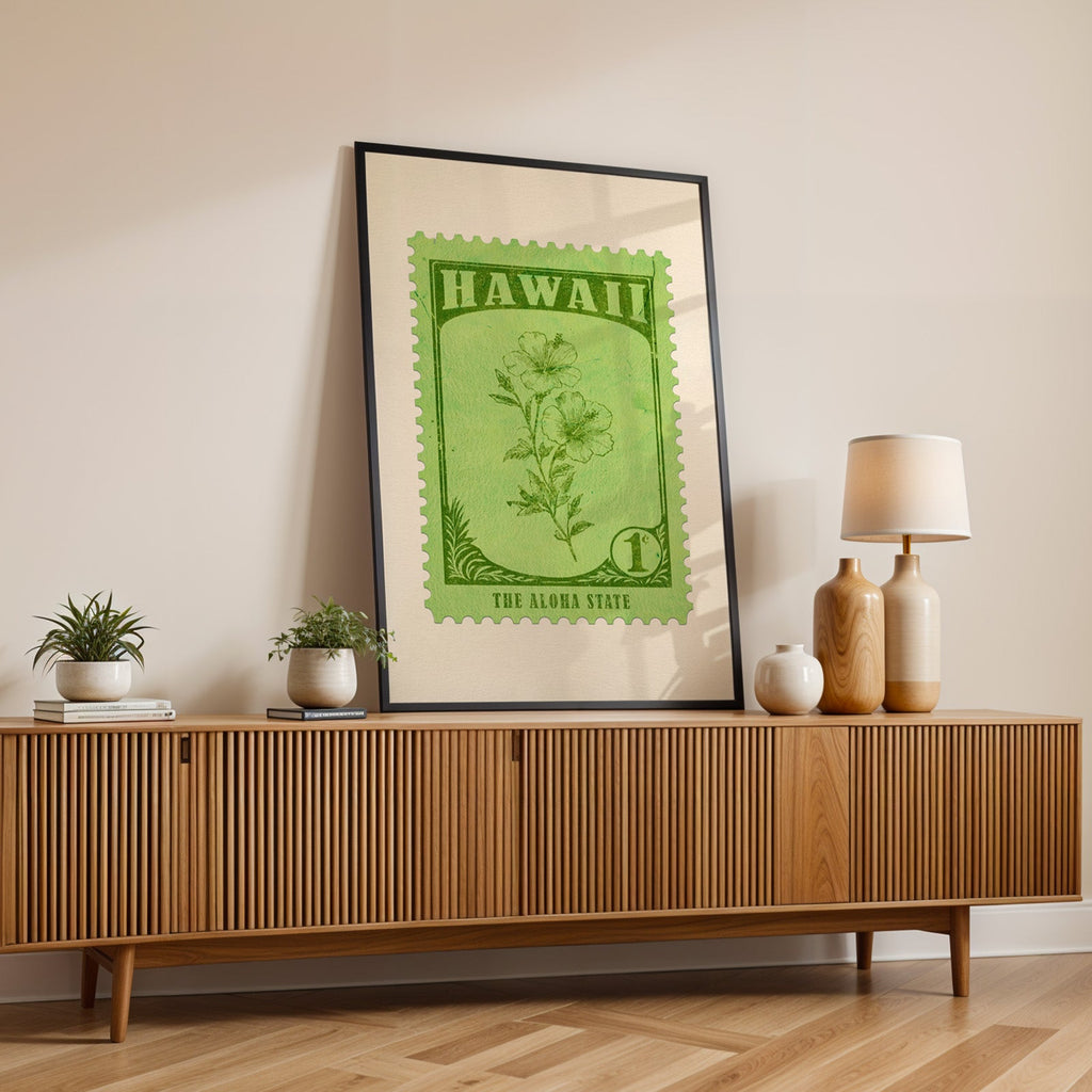Hawaii state flower print in a black frame leaning on a fluted wood credenza with vases and a lamp