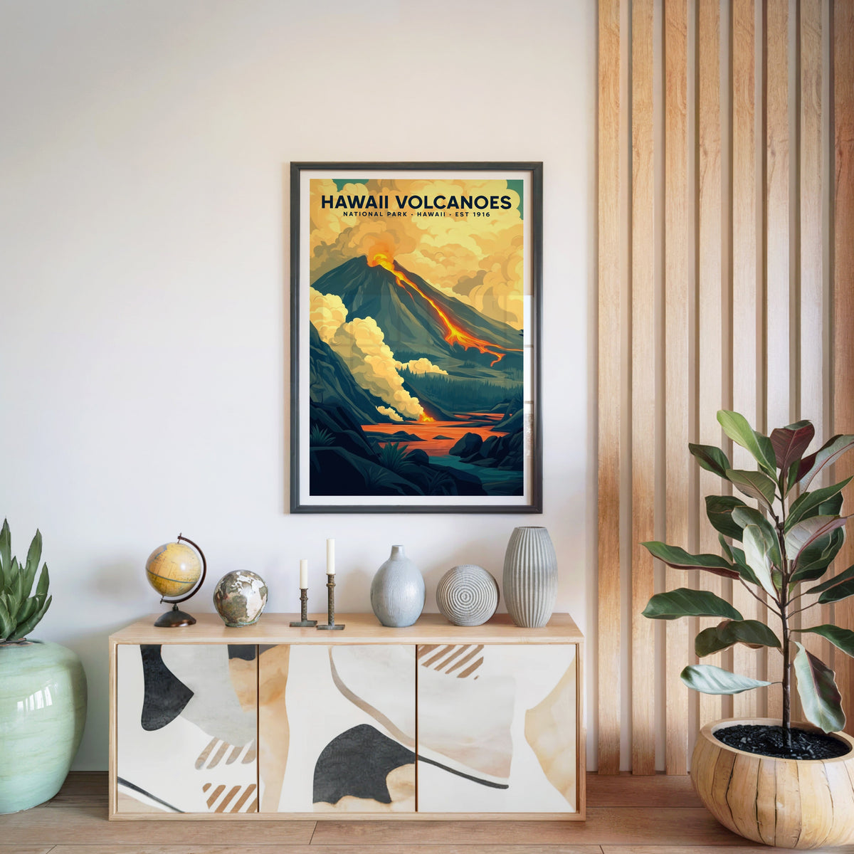 Hawaiʻi Volcanoes print in a black frame above a light wood sideboard with a globe and vases