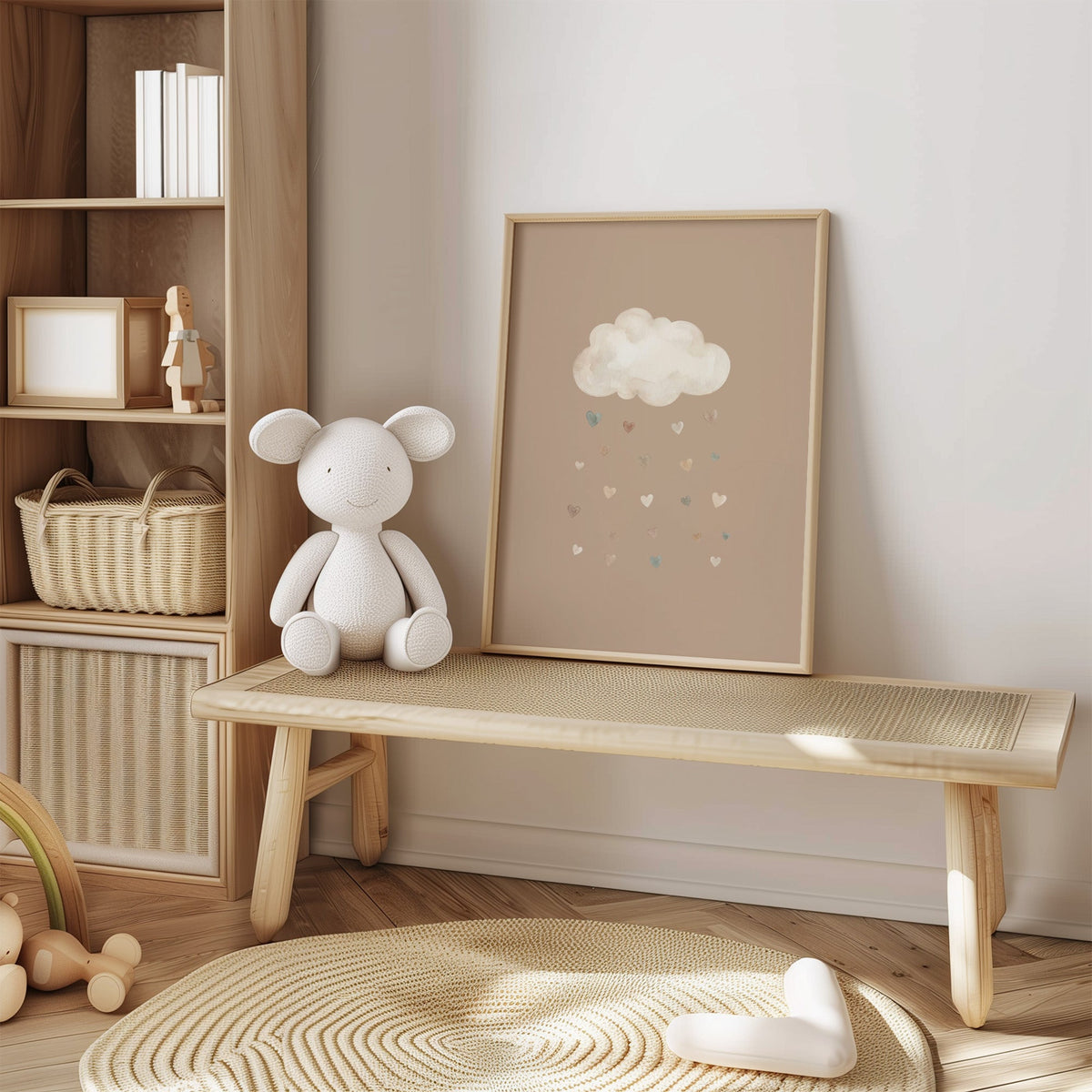 Cloud raining watercolor hearts on latte nursery print in an oak frame on a cane bench beside a white knit plush