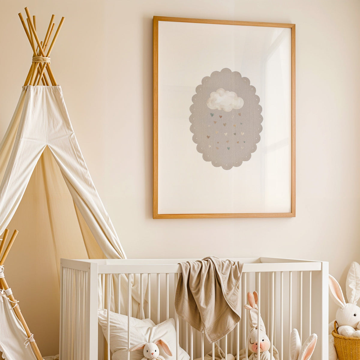 Cloud raining hearts in a scalloped oval nursery print in an oak frame above a white crib beside a canvas teepee